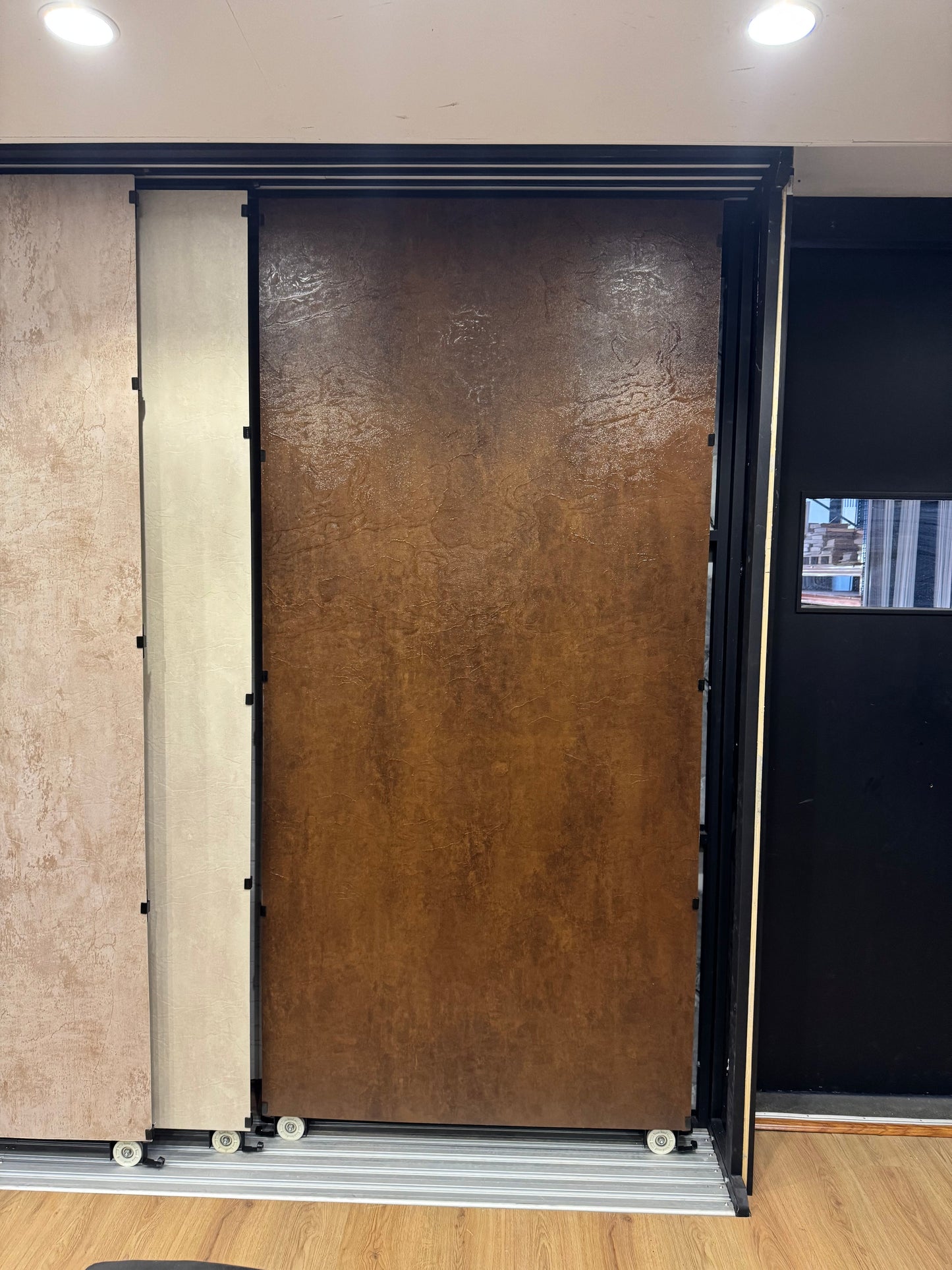 Showroom presentatie van een roestbruin SPC wandpaneel, tentoongesteld als losstaand display om de textuur en kleur van het paneel op de werkvloer te tonen.