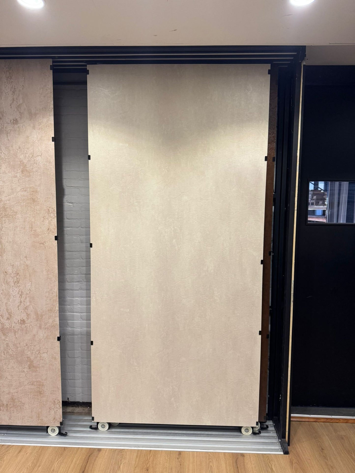 Beige betonlook SPC wandpaneel in showroom opstelling met grote plaat en strakke afwerking