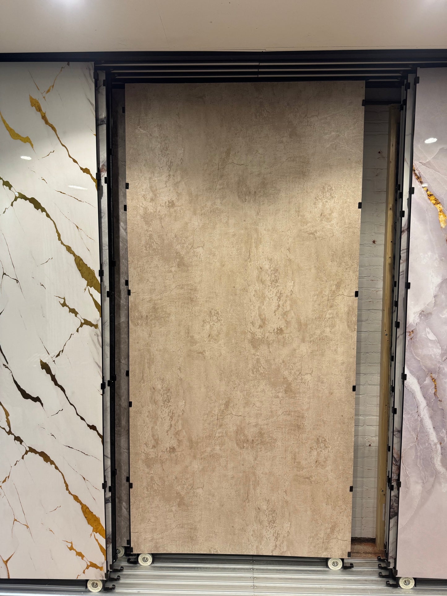 Groot beige betonlook SPC wandpaneel in showroomopstelling, gemonteerd in railsysteem en geschikt voor moderne wandafwerking